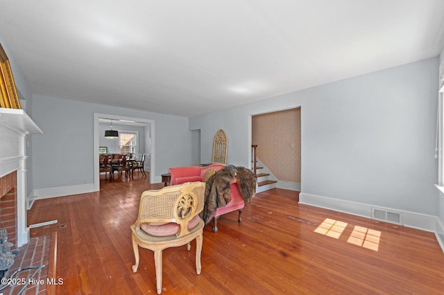 210 E 11th St, Washington, NC 27889 - living room featuring visible vents, a brick fireplace, baseboards, wood-type flooring, and stairs