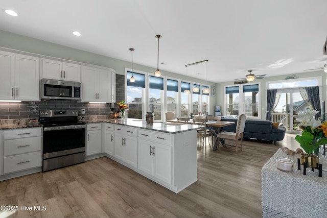 318 N Topsail Dr, Surf City, NC 28445 - kitchen with decorative backsplash, appliances with stainless steel finishes, a peninsula, and white cabinets