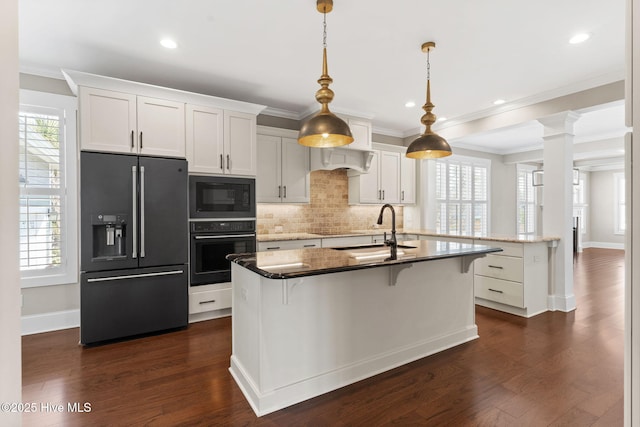 kitchen featuring black appliances, a kitchen island with sink, dark wood-style flooring, and a sink