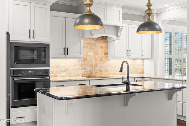 kitchen featuring wall oven, backsplash, built in microwave, an island with sink, and ornamental molding