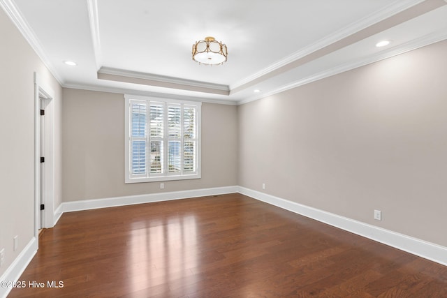 spare room with baseboards, a tray ceiling, and wood finished floors