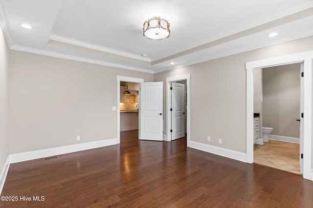 unfurnished bedroom featuring baseboards, ornamental molding, recessed lighting, wood finished floors, and a raised ceiling