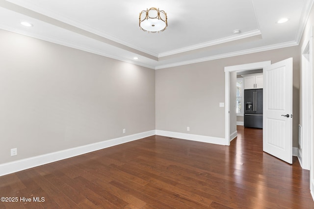 spare room featuring baseboards, a tray ceiling, recessed lighting, dark wood-type flooring, and crown molding