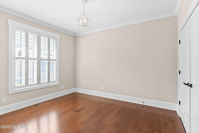 empty room with visible vents, ornamental molding, baseboards, and wood finished floors