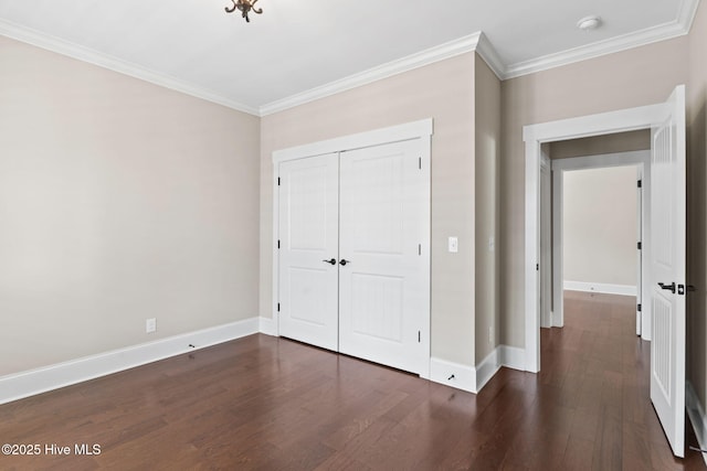 unfurnished bedroom with crown molding, baseboards, dark wood-style flooring, and a closet