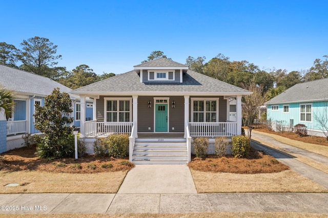 bungalow with covered porch and a shingled roof