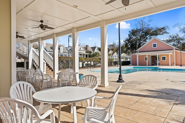 view of patio with outdoor dining space, an outbuilding, stairway, an exterior structure, and a community pool