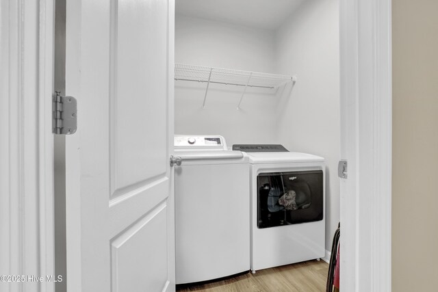 clothes washing area with light wood-style floors, laundry area, and washing machine and clothes dryer