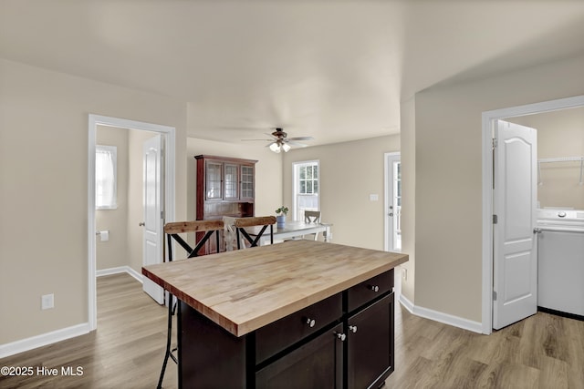 kitchen with light wood-type flooring, baseboards, butcher block counters, and a breakfast bar