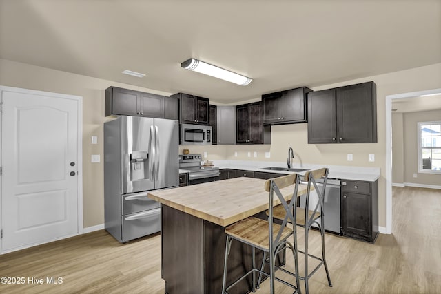 kitchen with baseboards, appliances with stainless steel finishes, wooden counters, and a sink