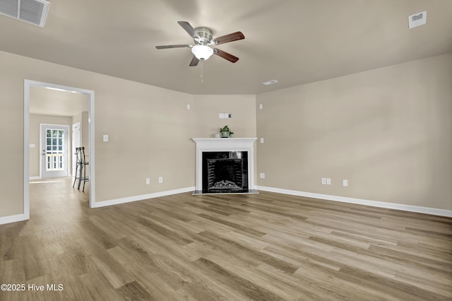 unfurnished living room with a fireplace, light wood-style floors, a ceiling fan, baseboards, and visible vents
