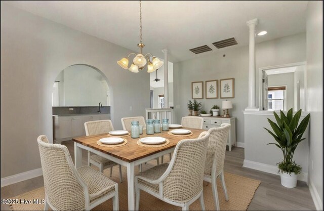 208 Carolina Beach Ave S # 300, Carolina Beach, NC 28428 - dining space with wood finished floors, a chandelier, baseboards, arched walkways, and ornate columns