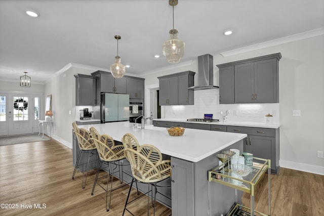 410 Sugar Cv, Wilmington, NC 28411 - kitchen featuring wall chimney exhaust hood, freestanding refrigerator, crown molding, light countertops, and a large island with sink