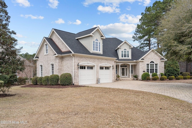 view of front facade with brick siding, a garage, driveway, and roof with shingles