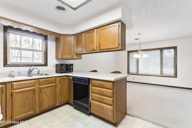 kitchen with a peninsula, black appliances, brown cabinets, and a sink
