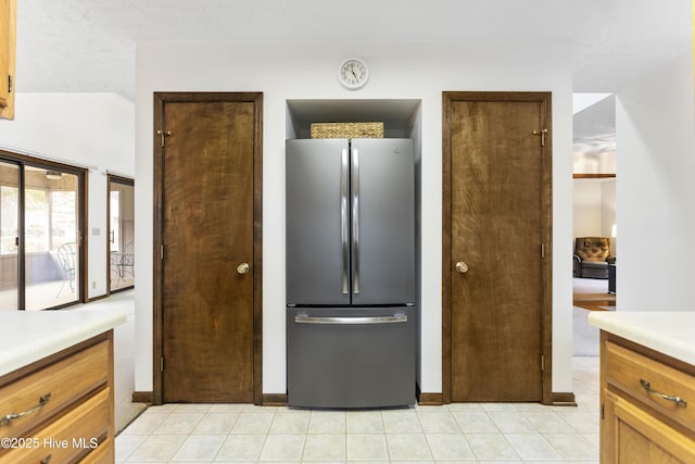 kitchen with freestanding refrigerator, light tile patterned flooring, baseboards, and light countertops