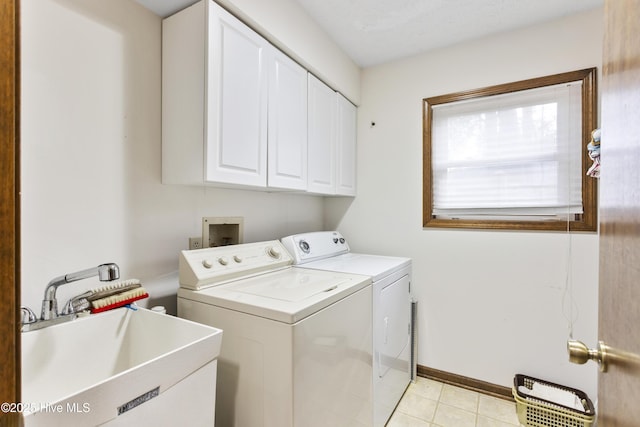 laundry area featuring washing machine and dryer, baseboards, a sink, cabinet space, and light tile patterned floors