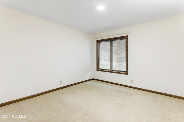 empty room with baseboards and light colored carpet