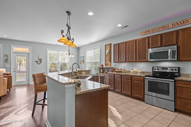 1203 Strange Ct, Morehead City, NC 28557 - kitchen with stainless steel appliances, a sink, a breakfast bar, pendant lighting, and light stone counters