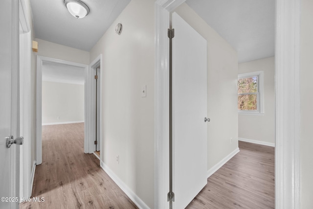 corridor featuring light wood-style floors and baseboards