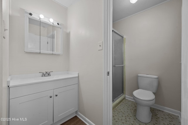 bathroom featuring a shower stall, toilet, vanity, and baseboards