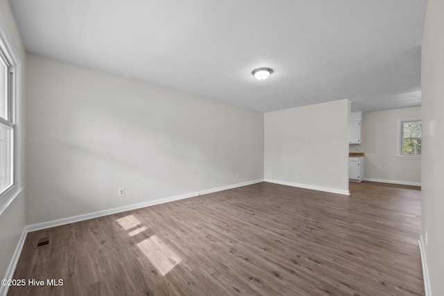 unfurnished room with visible vents, baseboards, and dark wood-style floors