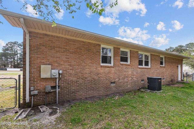 view of property exterior featuring brick siding, central AC unit, a lawn, and fence