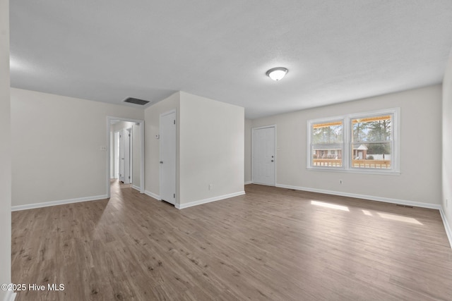 unfurnished living room with visible vents, baseboards, and wood finished floors