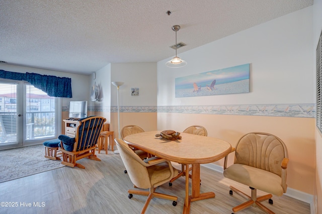 dining area featuring visible vents, a textured ceiling, and light wood-style floors