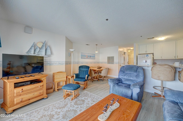 living room featuring a textured ceiling and light wood-type flooring