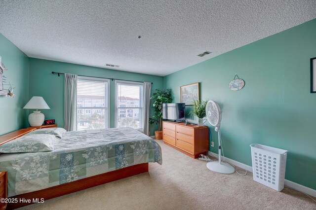 carpeted bedroom featuring baseboards, visible vents, and a textured ceiling