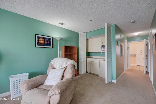 living area with a textured ceiling, light colored carpet, visible vents, and baseboards