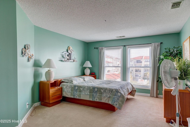 carpeted bedroom with visible vents, baseboards, and a textured ceiling