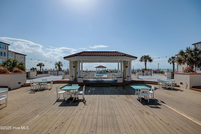 wooden terrace featuring a gazebo and outdoor dining area