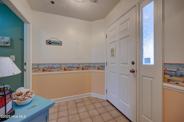 interior space featuring baseboards, a textured ceiling, and light tile patterned flooring