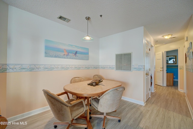 dining space with visible vents, a textured ceiling, and light wood-style floors