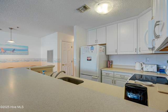 kitchen featuring visible vents, light countertops, white appliances, white cabinetry, and a sink