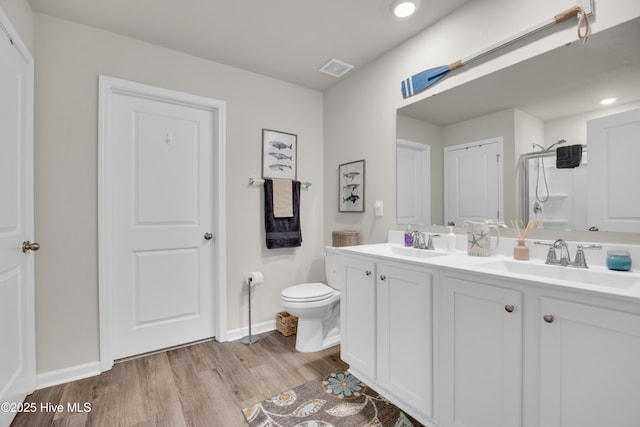 3659 Roseblossom Dr, Leland, NC 28451 - bathroom featuring a shower with door, toilet, double vanity, wood finished floors, and a sink