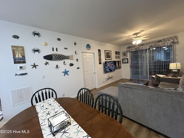 dining space with visible vents, a ceiling fan, baseboards, and wood finished floors