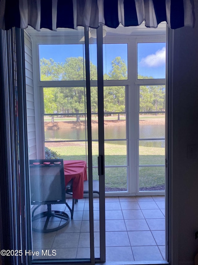 interior space with a water view, a healthy amount of sunlight, and tile patterned flooring