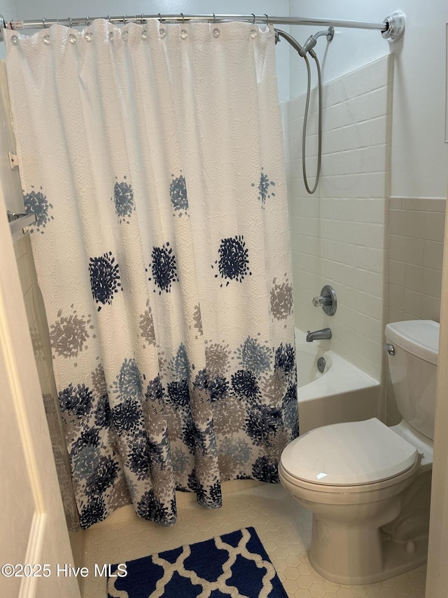 bathroom featuring wainscoting, toilet, tile walls, tile patterned floors, and shower / tub combo