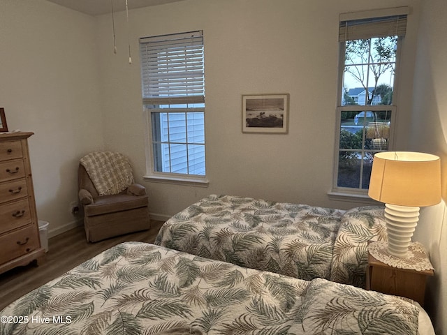 bedroom featuring baseboards, multiple windows, and wood finished floors