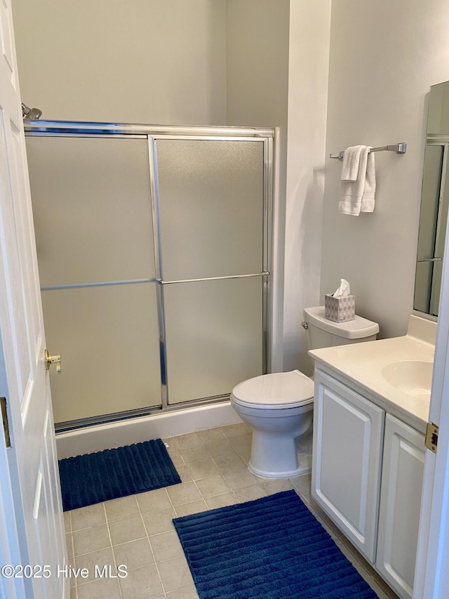 bathroom with vanity, a shower with shower door, tile patterned floors, and toilet