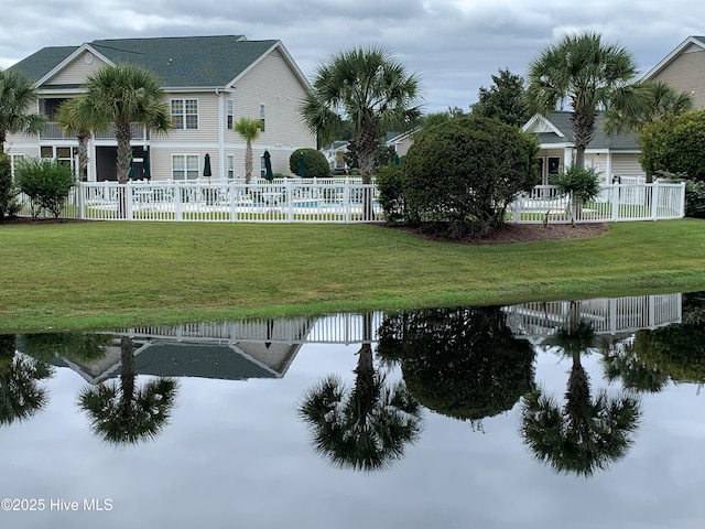 surrounding community featuring fence, a water view, and a yard