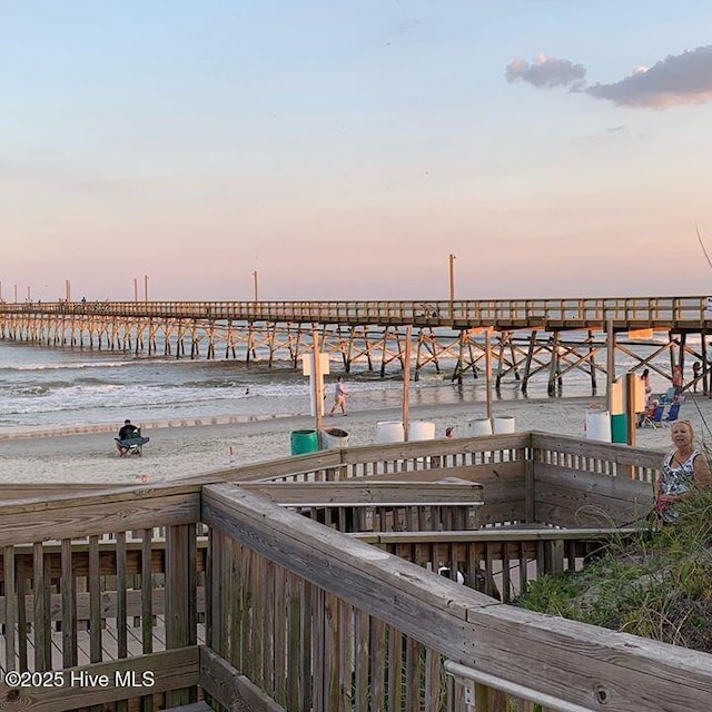 dock area with a water view, a view of the beach, and a pier
