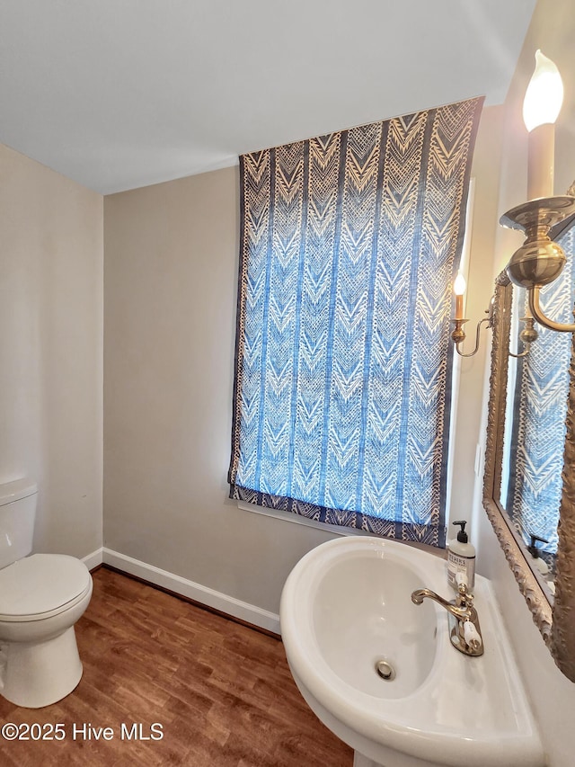 bathroom featuring baseboards, wood finished floors, and toilet
