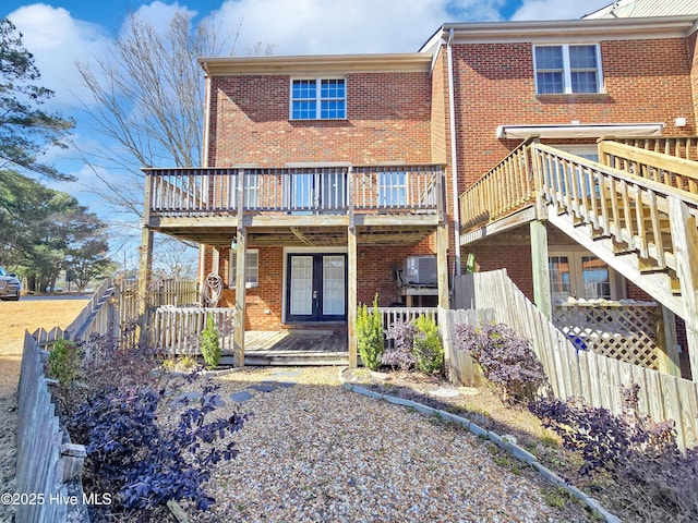 back of property featuring brick siding, fence, a wooden deck, and french doors