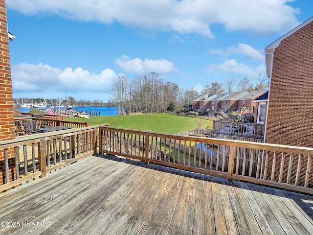 wooden deck with a water view and a lawn