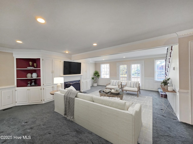 living area featuring a wainscoted wall, a wealth of natural light, dark carpet, and a decorative wall