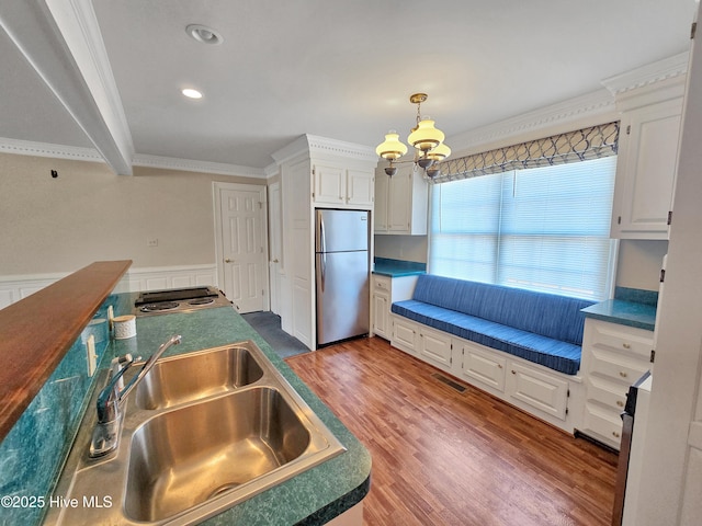 kitchen featuring visible vents, white cabinets, a sink, and freestanding refrigerator